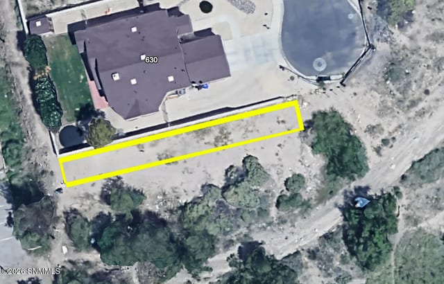 Aerial view of a narrow rectangular vacant lot beside a large home, outlined in yellow, in a Las Cruces neighborhood.